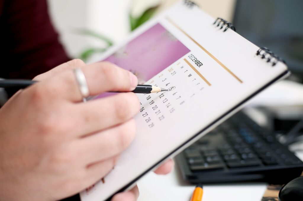 Eine Person hält einen Kalender 2026 und einen Bleistift.